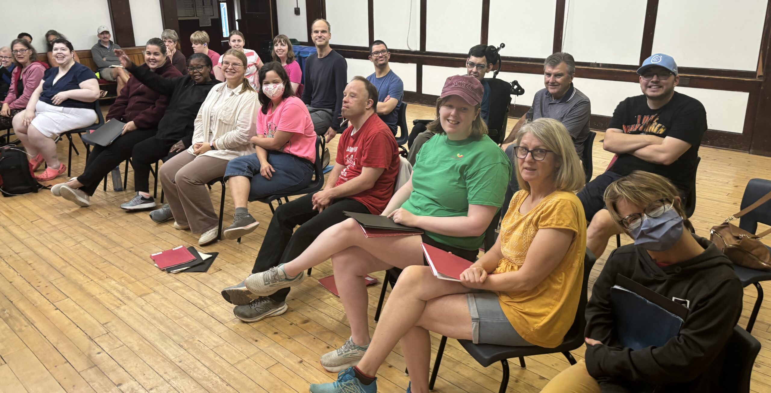 large group of people smiling and sitting in chairs together at an event