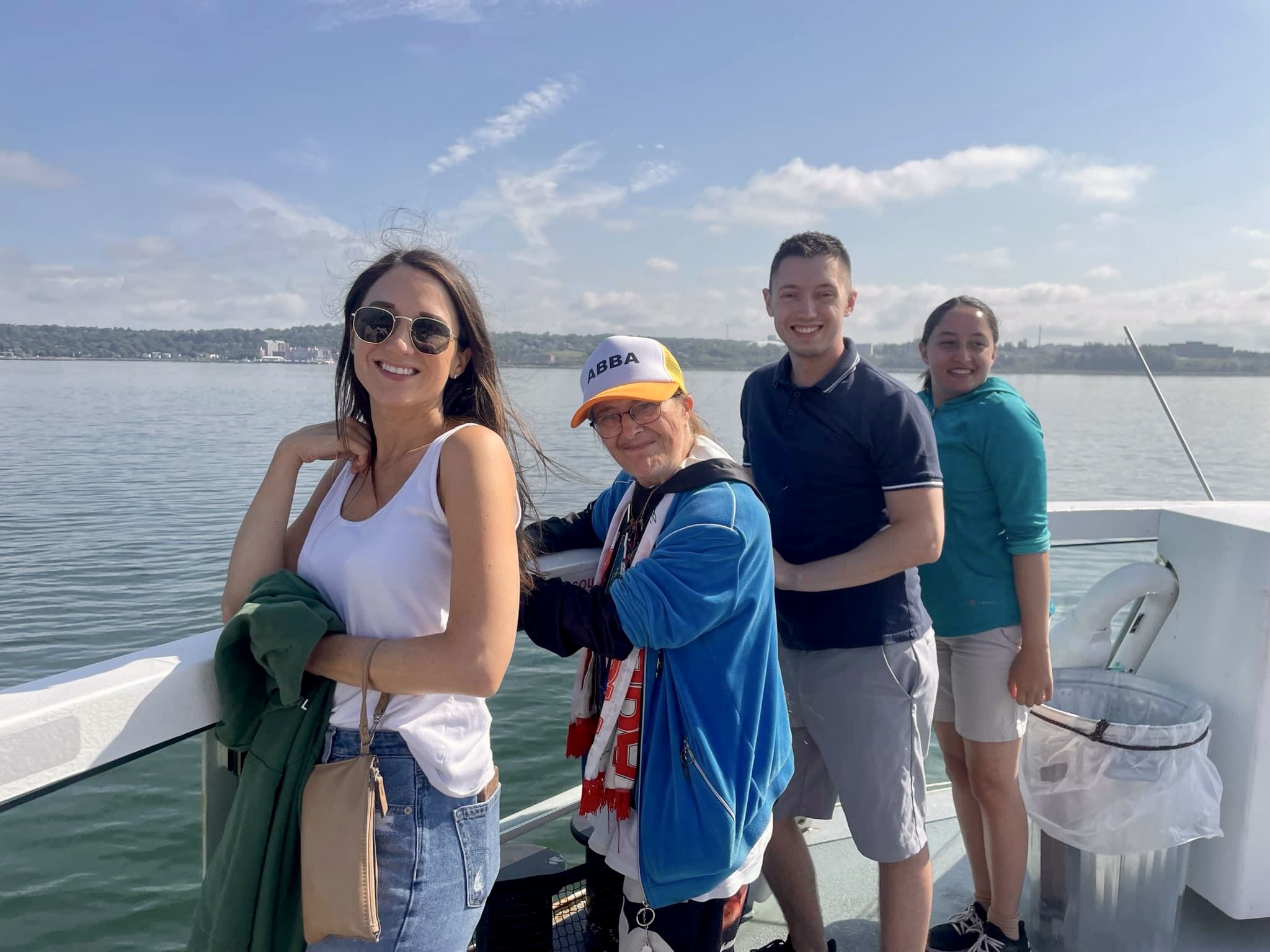 Four Prescott members stand along the railing of a ferry ship on a sunny summer day.