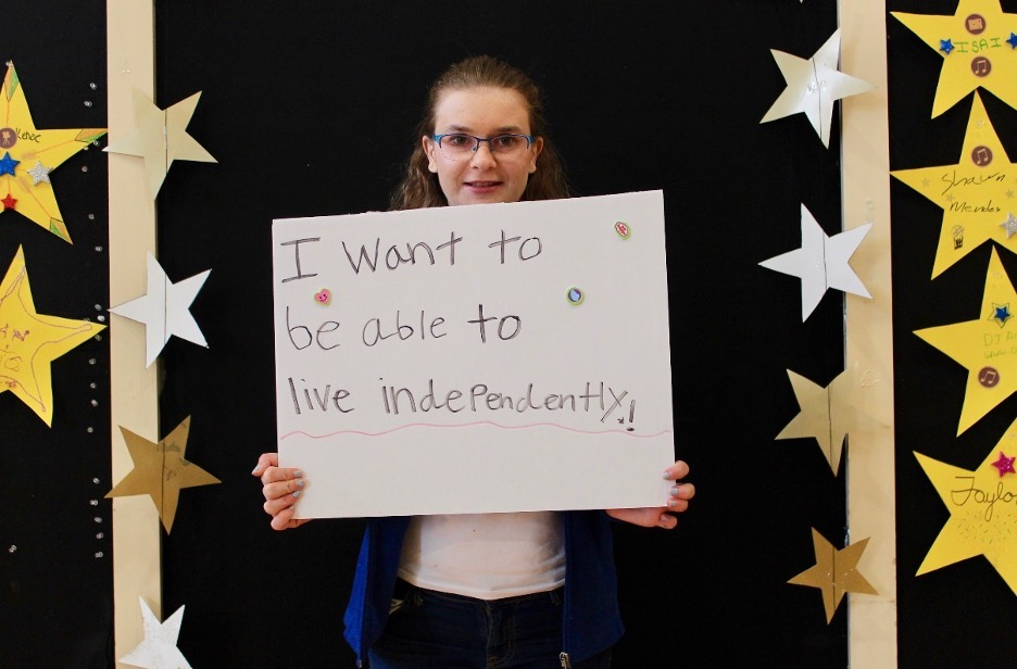 An individual seeking equal rights holds a sign that read "I want to be able to live independently"
