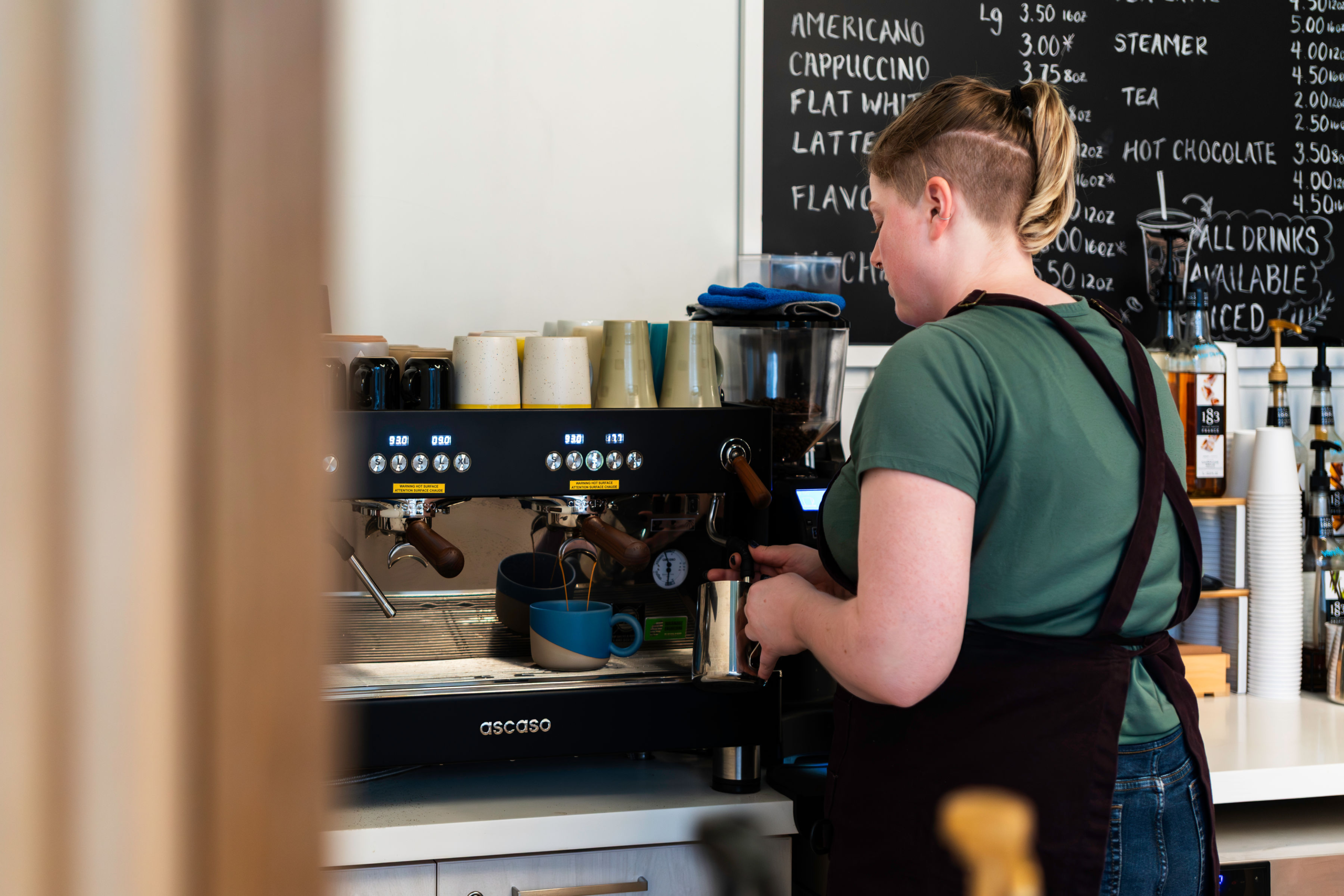 cafe team member is preparing a latte at the machine behind the counter at north end cafe