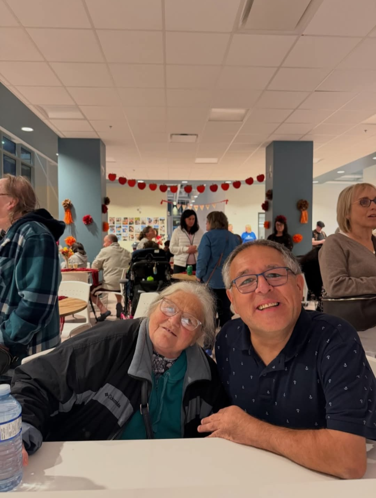 two people cmile while sitting together at a community event 